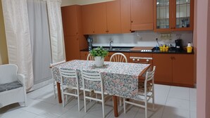 Una cocina compacta con armarios de madera, una mesa de comedor con sillas y una planta en maceta.