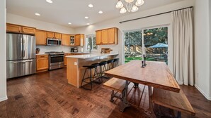 A modern kitchen with wooden cabinets, stainless steel appliances, and a large island with bar stools. - Mt. Bachelor Retreat! Hot tub, game room, family suite - great for large groups! (Bend)