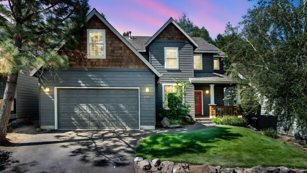 A two-story house with a garage, a well-maintained lawn, and a stone wall in the front yard. - Mt. Bachelor Retreat! Hot tub, game room, family suite - great for large groups! (Bend)