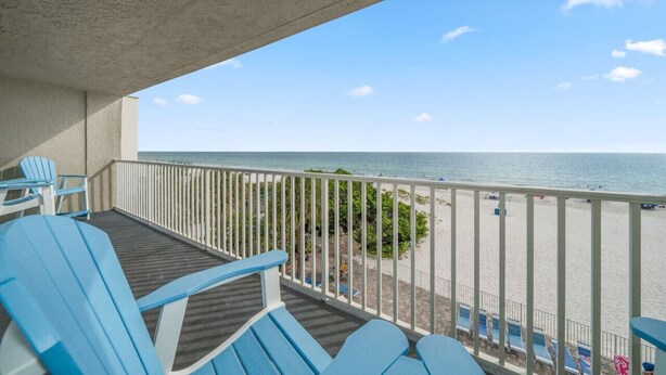 A balcony with blue chairs, a view of the beach, and a clear sky. - Sea Oats Condo #302 Direct Gulf with Heated Pool (Redington Shores)