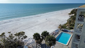 A beach view with a swimming pool and lounge chairs. - Sea Oats Condo #302 Direct Gulf with Heated Pool (Redington Shores)