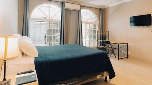 Een hotelkamer met een bed, bureau, lamp en televisie.