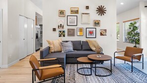 A modern living room with a grey sofa, two armchairs, a coffee table, and a patterned rug. - Cozy and Stylish Home, Convenient Location, Putting Green and Grill  (Chandler)