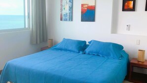Een slaapkamer met een groot bed, een raam met gordijnen en kunst aan de wanden.