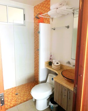 A bathroom with a shower, toilet, sink, and towel rack.