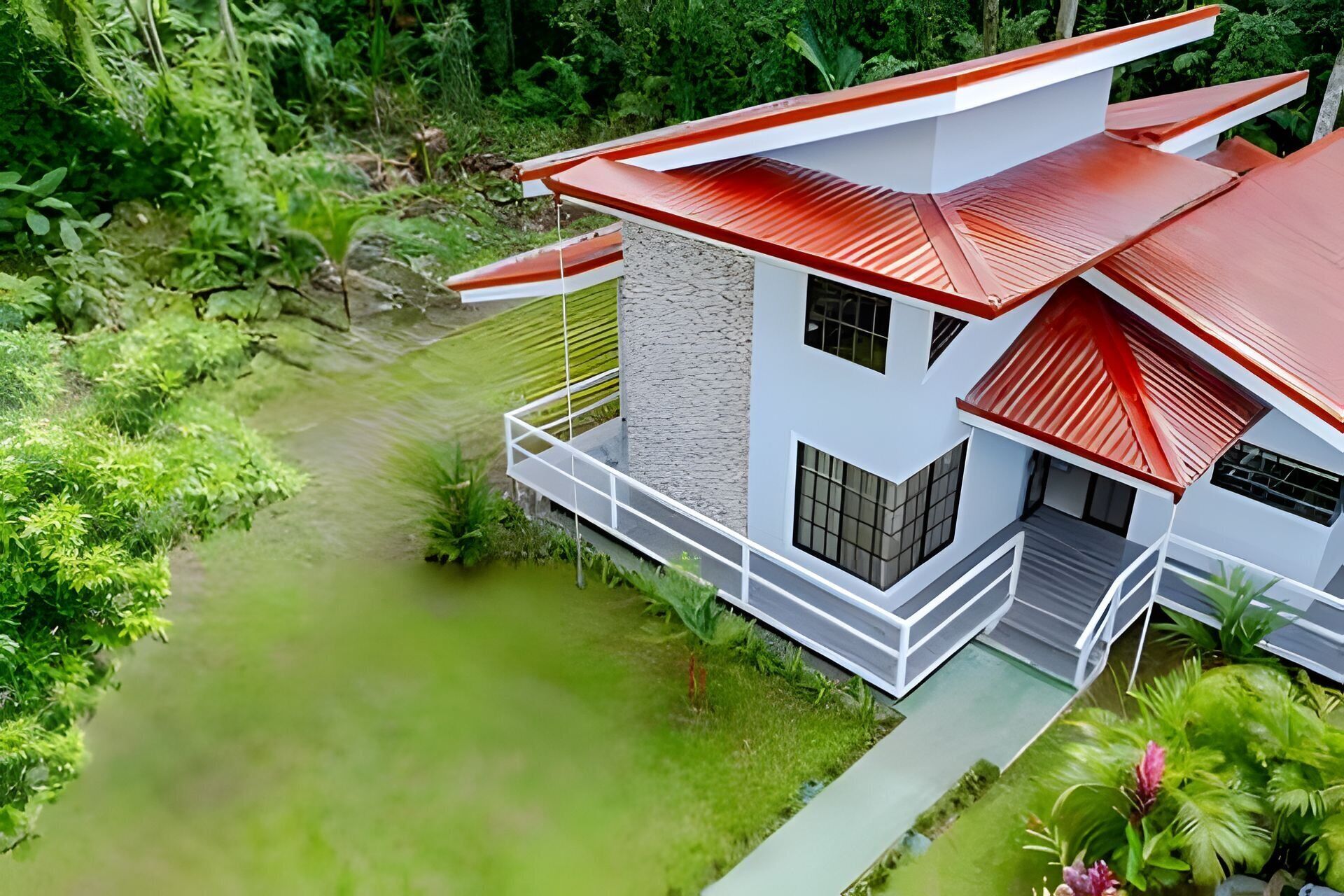 A modern two-story house with a red roof, white exterior walls, and a balcony.