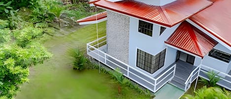 A modern two-story house with a red roof, white exterior walls, and a balcony.