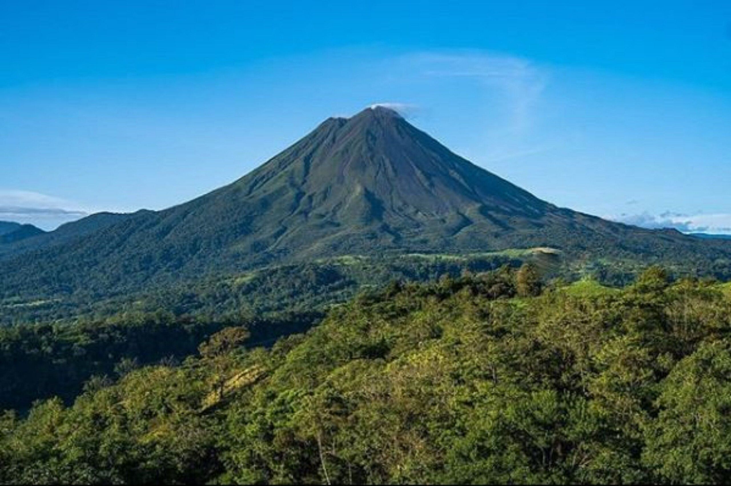 Una montaña con forma cónica y cima cubierta de nubes o humo.