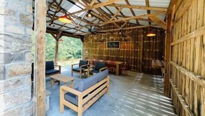 A rustic wooden interior with a stone wall, a wooden bench, and a table. - Redbird Hideaway With Hot Tub (Edmonson County)