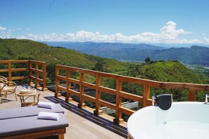 A wooden deck with a jacuzzi and lounge chairs overlooking a mountainous landscape. - La Perla Finca Hotel (Gigante)