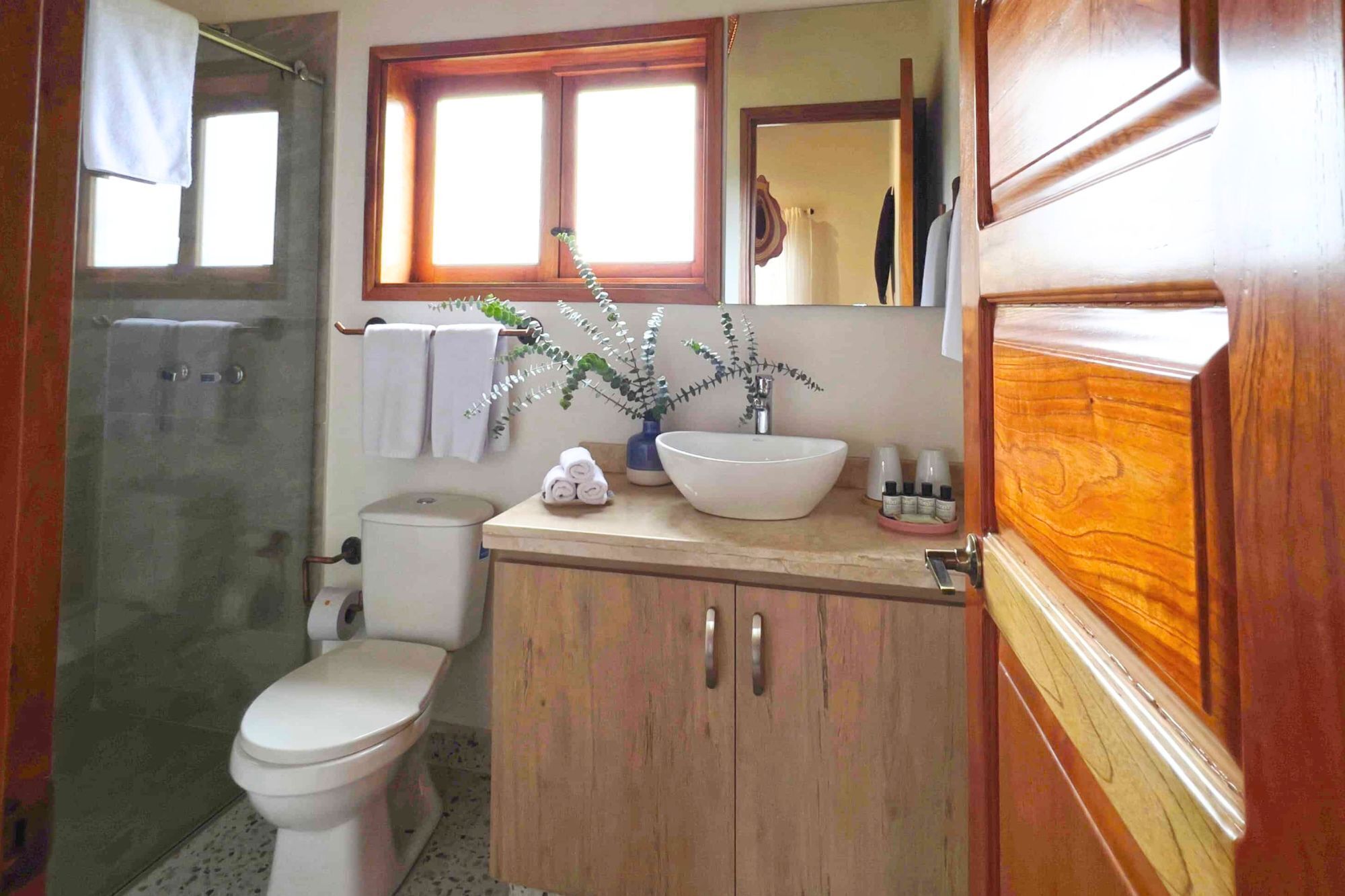 A bathroom with a toilet, a sink with a large mirror, and a shower area.
