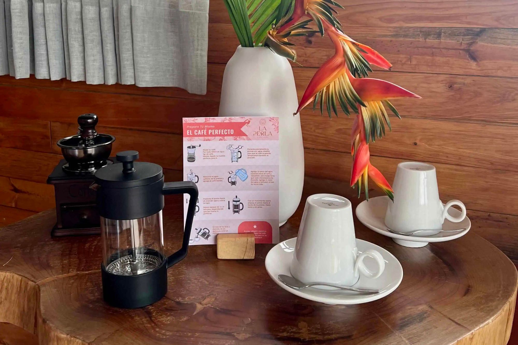A wooden table with a coffee maker, a coffee pot, a menu, and a plant.