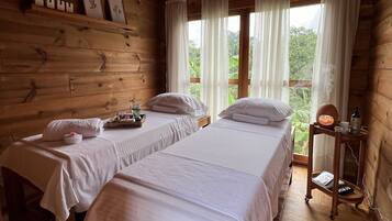 Cozy cabin room with two single beds, featuring a large window and wooden nightstand.