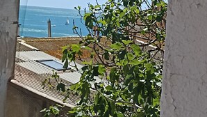 A view of a coastal area with a clear sky, a body of water, and a building with a sloped roof. - Renovated fisherman's cottage  (Sète)