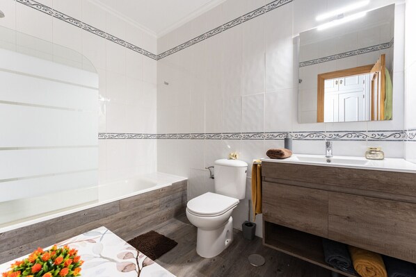Un baño moderno con bañera, inodoro y tocador.