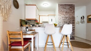 A modern kitchen with white cabinets, a brick accent wall, and a dining area with a wooden table and chairs. - MalagaSuite Yucas Fuengirola (Fuengirola)