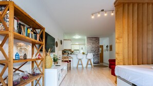 A modern, well-lit room with a wooden bookshelf, a small kitchen area, and a bed. - MalagaSuite Yucas Fuengirola (Fuengirola)