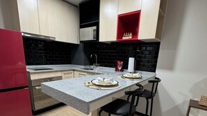 Une cuisine moderne dotée d’un îlot central, de meubles de rangement noirs et blancs et d’un réfrigérateur rouge.