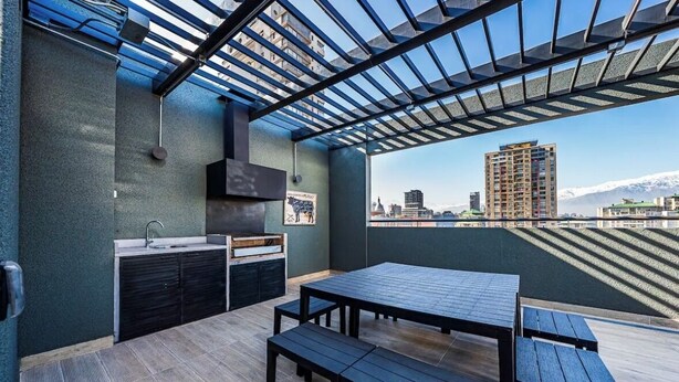 Une terrasse sur le toit comprenant un espace cuisine, avec un évier et un barbecue, ainsi qu’une table avec des bancs.
