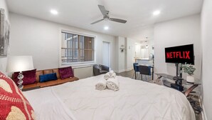 A hotel room with a bed, a desk, a TV, and a ceiling fan. - Skyline Vistas | Downtown | Perfect Romantic Getaways (Atlanta)