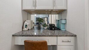 A kitchen with white cabinets, a granite countertop, a coffee maker, and a toaster. - Skyline Vistas | Downtown | Perfect Romantic Getaways (Atlanta)