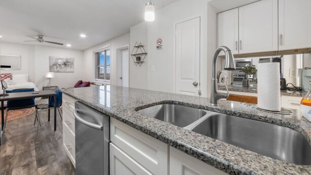 A modern kitchen with granite countertops, stainless steel appliances, and white cabinetry. - Skyline Vistas | Downtown | Perfect Romantic Getaways (Atlanta)