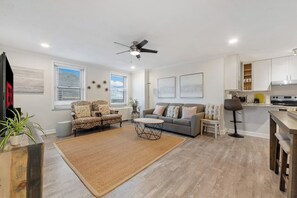 A modern living room with a sofa, coffee table, and a dining area with a kitchen in the background. - Terrace, Skyline View, Downtown, Restaurant & Bars (Atlanta)