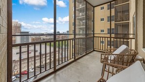 A balcony with a view of a parking lot and buildings.