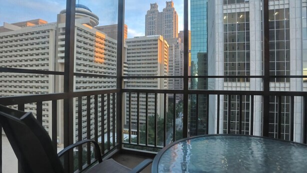 A balcony with a glass table and chairs, overlooking a cityscape with modern buildings. - 1BR Apt,Centrally located, City View (Atlanta)