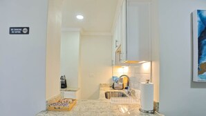 A modern kitchen with a granite countertop, a sink, and a coffee machine. There is a sign indicating no smoking or vaping. - 1BR Apt,Centrally located, City View (Atlanta)