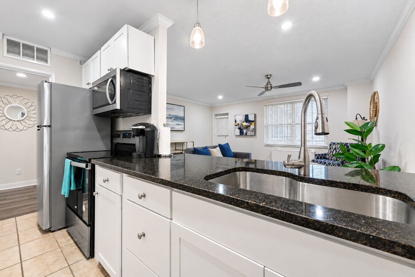 A modern kitchen with a stainless steel sink, white cabinets, and a black countertop.