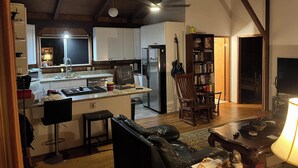 Uma cozinha acolhedora com uma ilha central, uma sala de jantar com sofá de couro e uma estante repleta de livros.