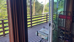 Quarto com porta de vidro deslizante que dá para um deck com guarda-corpo de madeira, um banco acolchoado e um espaço para vinhos com garrafas.