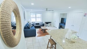 Una sala de estar moderna con un sofá, una mesa de centro y una cocina con encimera de granito y pileta.
