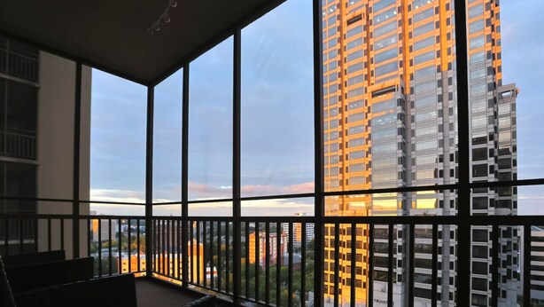 Un balcon donnant sur un grand immeuble au coucher du soleil.