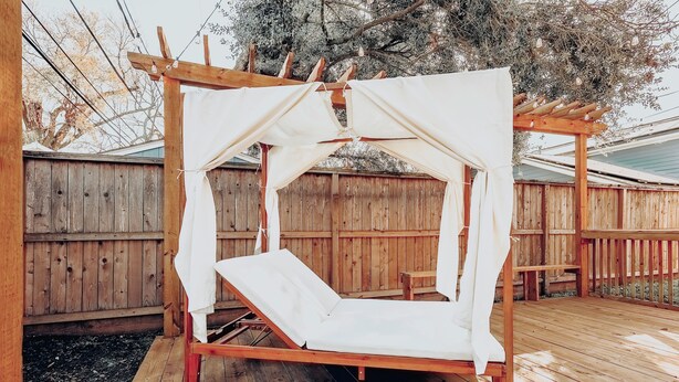 Una terraza de madera con una cama con dosel blanco.