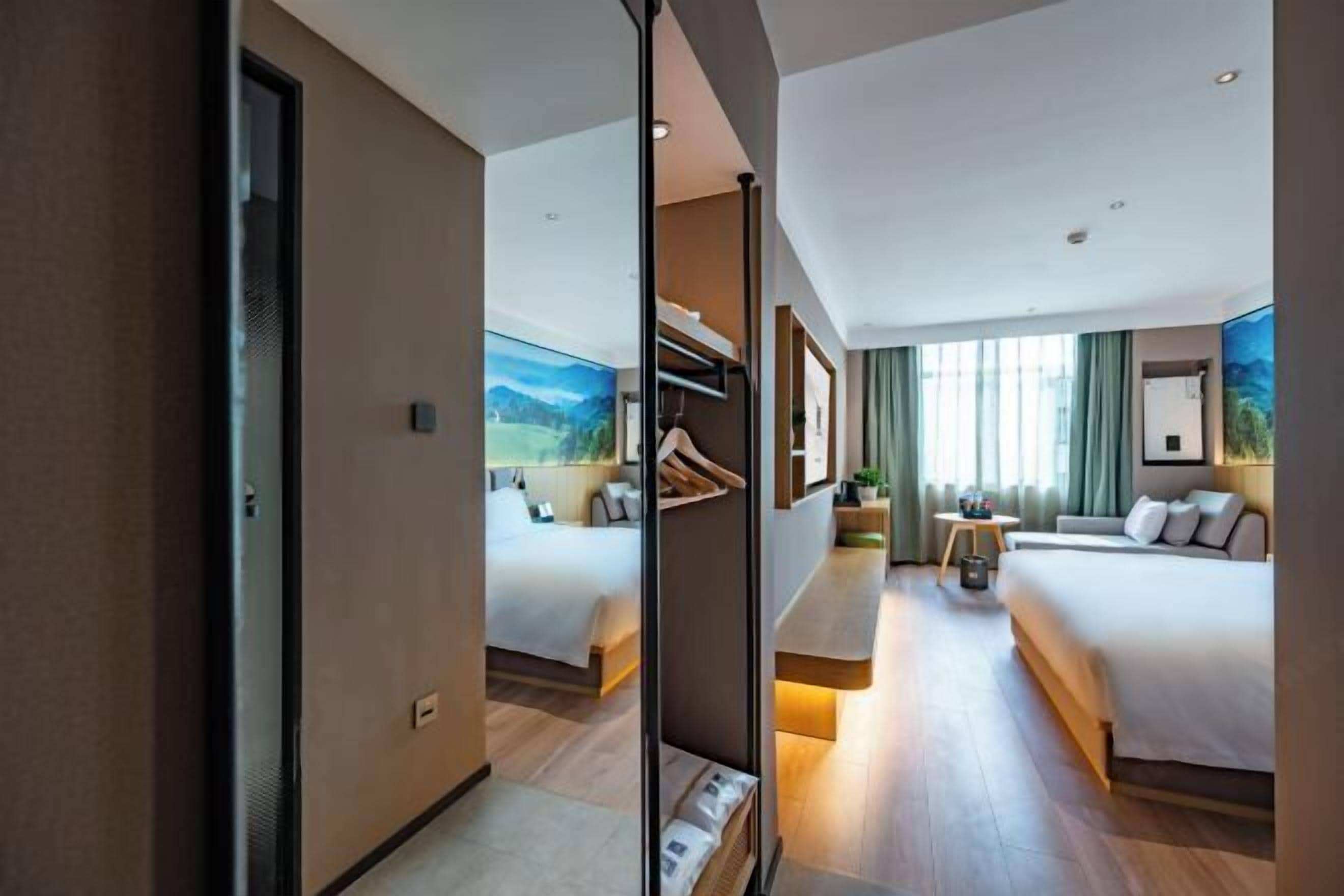 Une chambre d’hôtel avec un grand lit, un lit plus petit, un bureau et une vue sur l’extérieur.