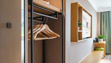 Een moderne hotelkamer met een houten bankje, een wandplank met een plant erop en een ingelijst beeld.