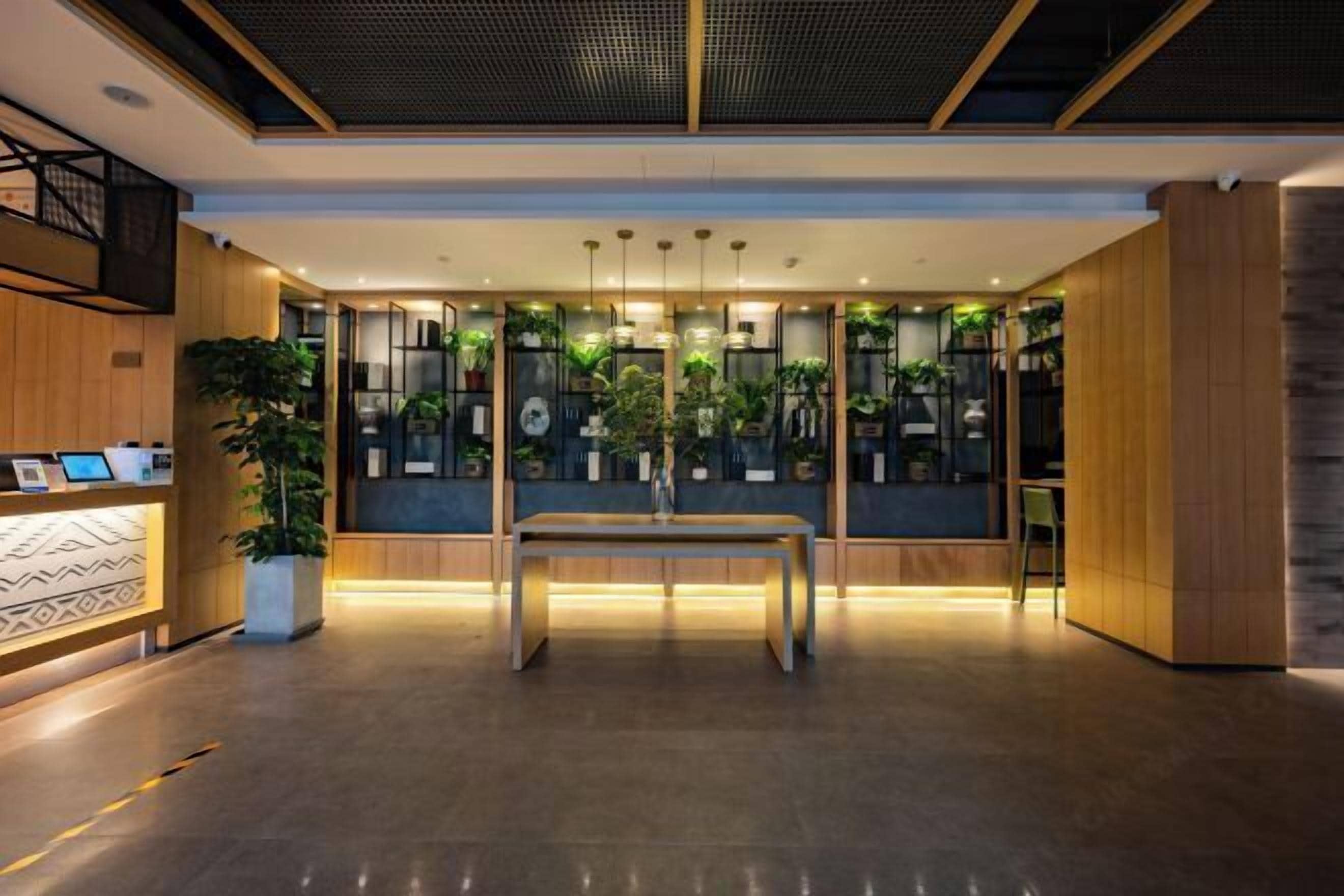 A modern lobby with a reception desk, a central table, and vertical plant installations.