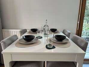 A dining table set with black bowls and plates, a bottle, and glasses. - 3-room apartment at the foot of the Stade de France (Saint-Denis)