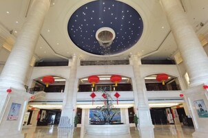 A spacious lobby with a high ceiling, large columns, and a central fountain.