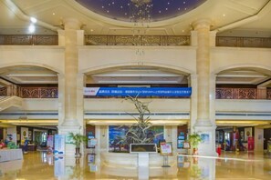 A spacious lobby with a high ceiling, large columns, and a central decorative tree. - Hengshui Taihua Boyue Hotel (Hengshui)