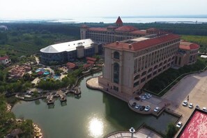 Ein großes Hotel mit einem Hauptgebäude, Uferlage und einer kleinen Insel mit Anlegestellen.