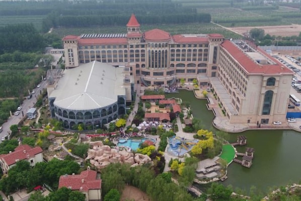 A large hotel with a central courtyard, multiple wings, and a body of water.