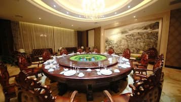 A round dining table with chairs, a chandelier, and a painting on the wall.
