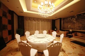 A round dining table with chairs, a chandelier, and a painting on the wall. - Hengshui Taihua Boyue Hotel (Hengshui)