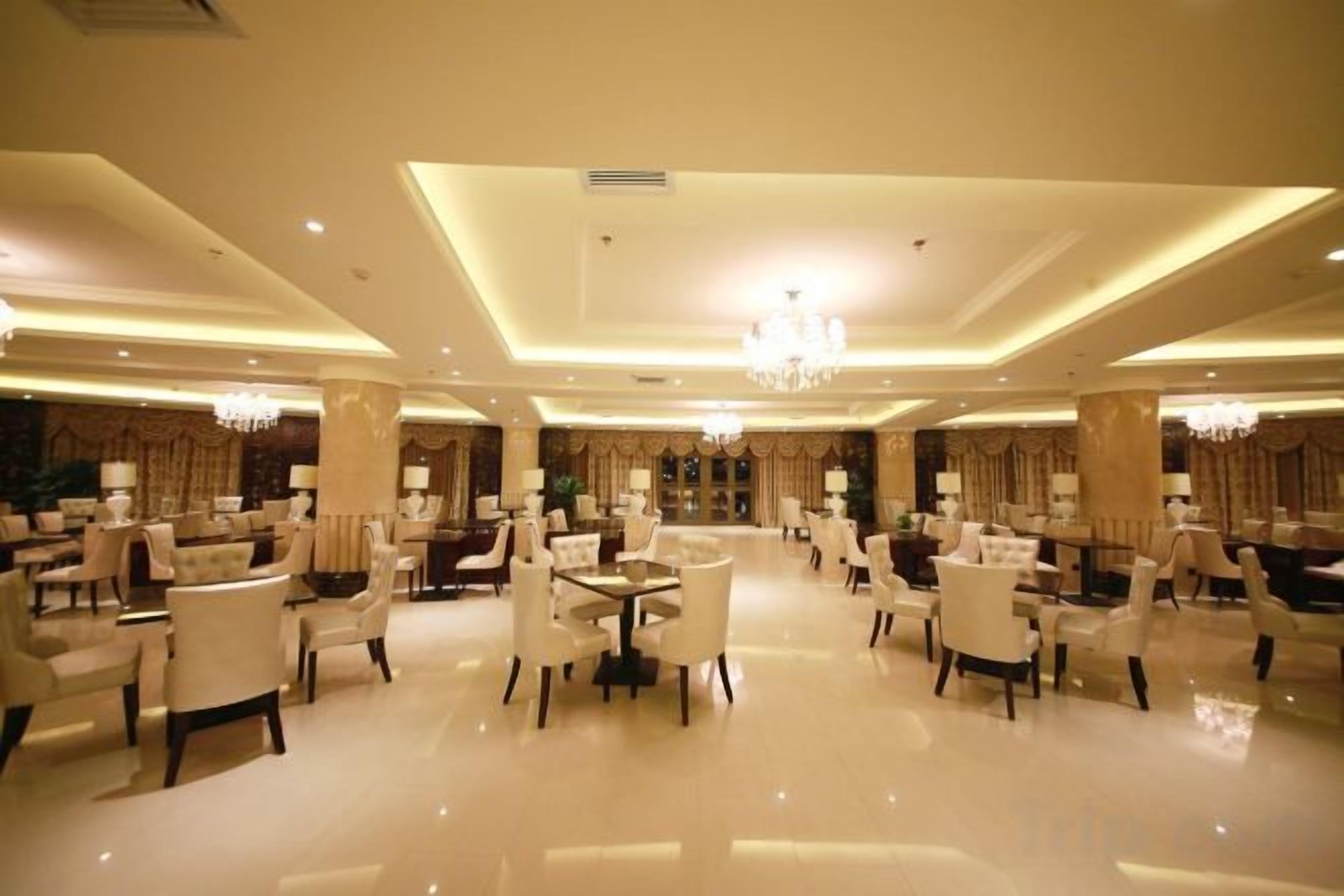 Un amplio vestíbulo de hotel con varias zonas de estar, candelabros y una columna decorativa central.