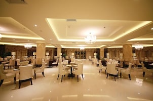 A spacious hotel lobby with multiple seating areas, chandeliers, and a central decorative column.