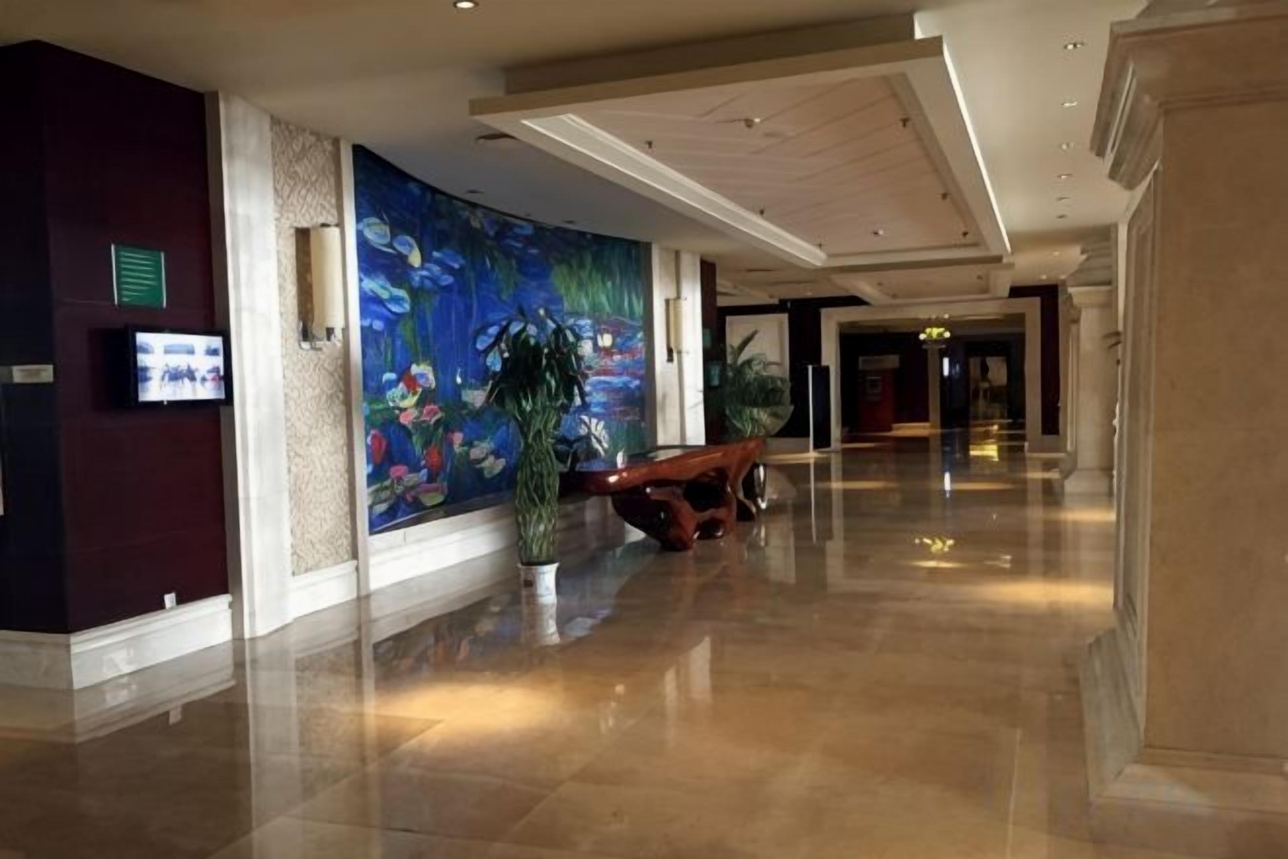 A hotel lobby with a large mural, a reception desk, and a polished floor.
