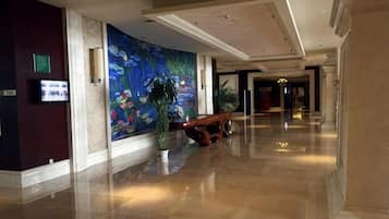 A hotel lobby with a large mural, a reception desk, and a polished floor.